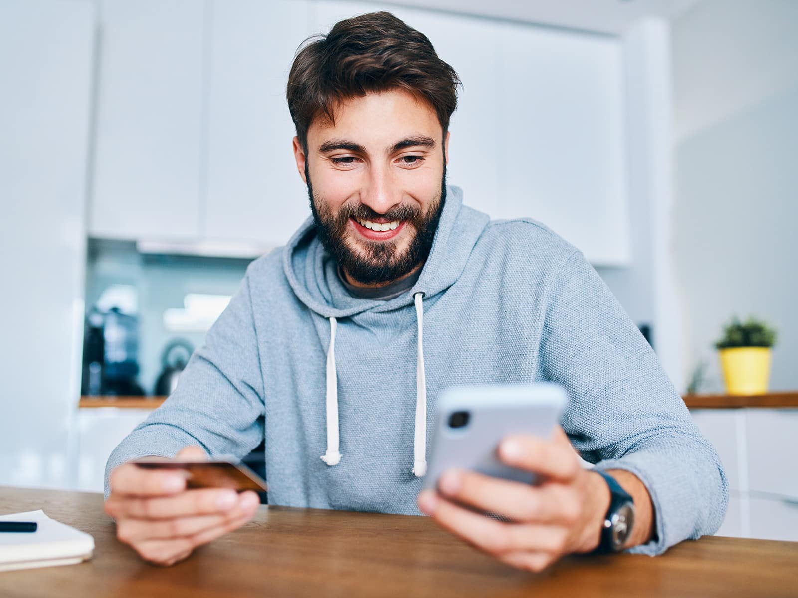 Guy in grey sweatshirt holding phone and credit card