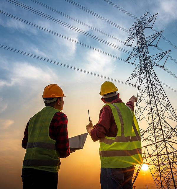Electrical Contractors Wearing Reflective Vests Pointing At Powerlines