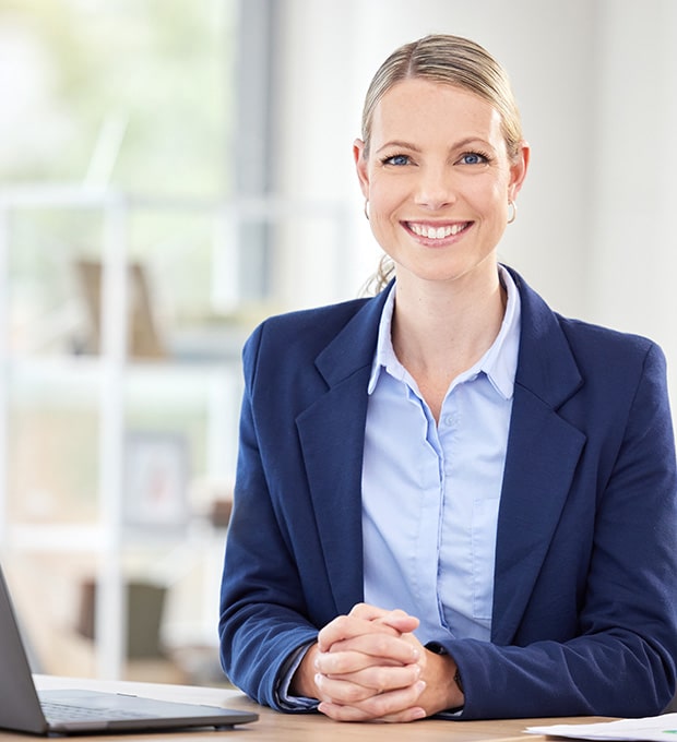 Lady With Suit Jacket Smiling Sitting At Desk