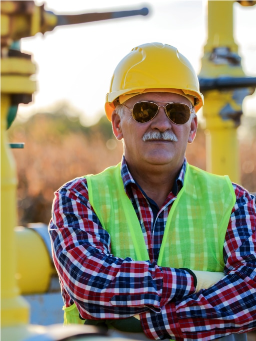 Older Contractor In Yellow Vest And Hardhat Crossing Arms